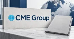 Large official cyan globe and navy CME Group wordmark on a stone sign beside an unbranded greyscale contract folder, with a muted globe in the background.