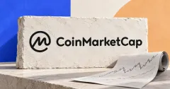 Large official black CoinMarketCap symbol and wordmark on an off-white stone sign beside an unbranded greyscale paper market-chart roll, against cobalt and apricot panels.