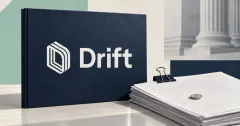 One large official white Drift symbol and wordmark on a navy stone folio beside unbranded greyscale recovery paperwork, a steel binder clip and a small plain coin, against off-white, navy and mint panels.