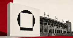 Large official black Galaxy logo mark on an off-white stadium sign beside a greyscale college-football stadium facade and lights, over red and off-white editorial panels.