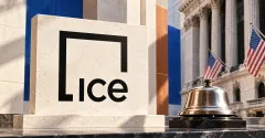 One large official black ICE square-frame logo on an ivory stone sign beside a smaller unbranded metallic trading bell, with cobalt and copper panels and an exchange facade behind them.