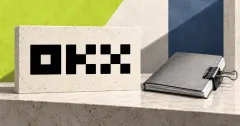 Large official black OKX wordmark on an ivory stone desk sign beside a smaller unbranded greyscale document folio secured shut with a metal binder clip, against lime and slate-blue panels.