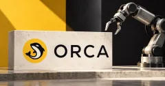 One large official yellow Orca whale emblem and black ORCA wordmark on an off-white stone sign beside an unbranded greyscale industrial robot arm, against mustard-yellow and charcoal architectural panels.