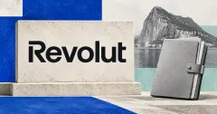 Large official black Revolut wordmark on an off-white limestone sign beside a smaller unbranded greyscale custody folder with a steel clasp, with the Rock of Gibraltar behind it and cobalt-blue and seafoam panels.