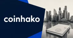 Official white Coinhako wordmark on a large navy editorial panel beside a greyscale Singapore financial skyline and an unbranded approval dossier, representing SBI Holdings' majority acquisition of Coinhako.