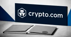 Large official white Crypto.com lion mark and wordmark on a navy plaque above a greyscale torn, unbranded financial-agreement folder on an off-white editorial background.